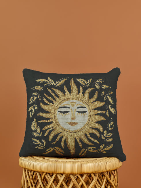 Black woven throw pillow with golden embroidered sun and laurel design, featuring a serene celestial face with closed eyes.
