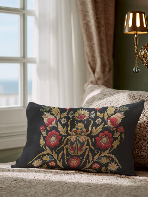 A rectangular black lumbar pillow with a premium linen-feel texture. The pillow features a detailed, tapestry-style Art Nouveau print of a large scarab beetle at its center. The beetle and surrounding symmetrical floral and botanical motifs are rendered in rich colors of antique gold, deep crimson red, and muted teal. This ornate, maximalist design is set against a dark charcoal black background, creating a moody, gothic, & scholarly aesthetic suitable for dark academia or victorian home decor.