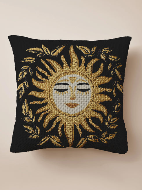 Black woven throw pillow with golden embroidered sun and laurel design, featuring a serene celestial face with closed eyes.