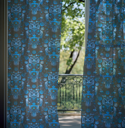 A sheer curtain panel featuring a repeating pattern of stylized owls in luminous blue tones, surrounded by delicate botanical flowers and flourishes on a dark background.