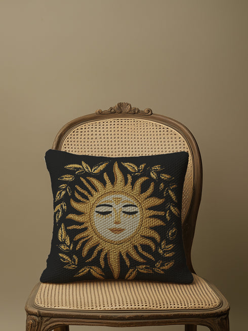 Black woven throw pillow with golden embroidered sun and laurel design, featuring a serene celestial face with closed eyes.