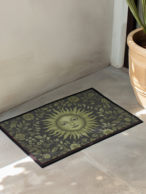 Witchy home décor doormat with an enchanting olive green sun face surrounded by flowing botanicals and foliage on a rich black background, ideal for adding earth-centered mysticism to any entrance.