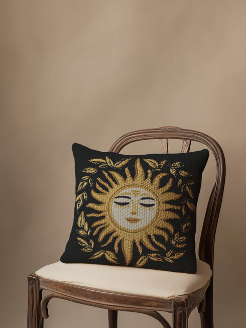 Black woven throw pillow with golden embroidered sun and laurel design, featuring a serene celestial face with closed eyes.
