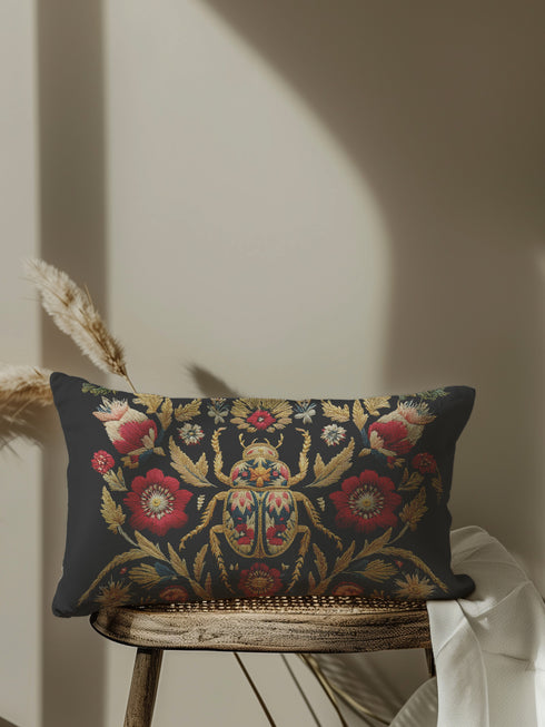 A rectangular black lumbar pillow with a premium linen-feel texture. The pillow features a detailed, tapestry-style Art Nouveau print of a large scarab beetle at its center. The beetle and surrounding symmetrical floral and botanical motifs are rendered in rich colors of antique gold, deep crimson red, and muted teal. This ornate, maximalist design is set against a dark charcoal black background, creating a moody, gothic, & scholarly aesthetic suitable for dark academia or victorian home decor.