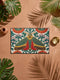 Rectangular low profile doormat printed on a cream ground with a faux embroidery effect that imitates raised satin stitch. A large symmetrical moth sits at the center with teal green wings, mustard yellow upper edges, and deep red lower wing markings. Surrounding it are oversized burnt orange and red blooms, winding green foliage, and clusters of small pink flower buds. A solid black trim frames all four edges of the flat, one sided printed surface.