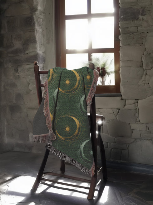 Forest green cotton throw blanket with woven silver moon phases and golden sun motifs, finished with multicolored fringe trim.