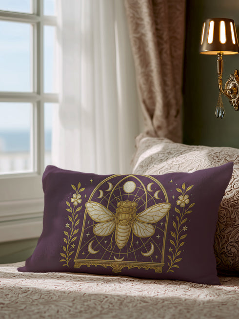 A rectangular lumbar pillow cover in a deep, moody plum-purple. The pillow features a detailed, symmetrical design in a shimmering gold color. In the center is a large, ornate cicada with translucent, veined wings, facing forward. The cicada is framed by a gothic-style archway with intricate patterns. Above the arch is a full moon, flanked by waxing and waning crescent moon phases. The design is bordered by vertical botanical vines with small flowers and stars, completing the mystical aesthetic.