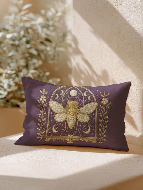 A rectangular lumbar pillow cover in a deep, moody plum-purple. The pillow features a detailed, symmetrical design in a shimmering gold color. In the center is a large, ornate cicada with translucent, veined wings, facing forward. The cicada is framed by a gothic-style archway with intricate patterns. Above the arch is a full moon, flanked by waxing and waning crescent moon phases. The design is bordered by vertical botanical vines with small flowers and stars, completing the mystical aesthetic.