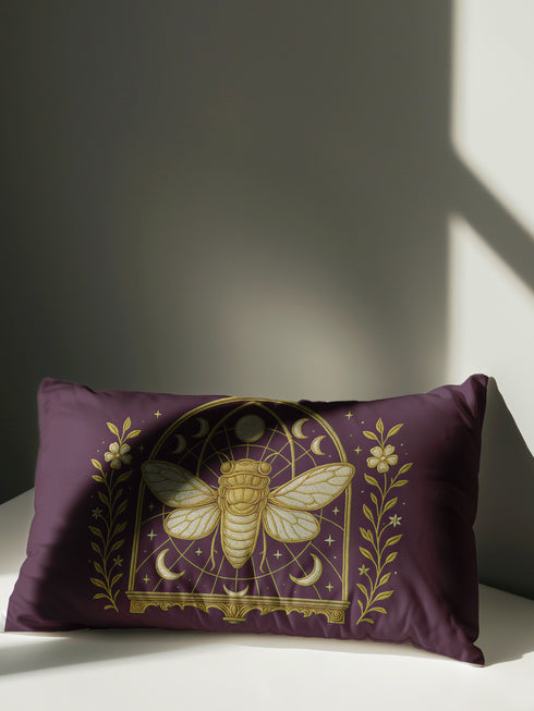 A rectangular lumbar pillow cover in a deep, moody plum-purple. The pillow features a detailed, symmetrical design in a shimmering gold color. In the center is a large, ornate cicada with translucent, veined wings, facing forward. The cicada is framed by a gothic-style archway with intricate patterns. Above the arch is a full moon, flanked by waxing and waning crescent moon phases. The design is bordered by vertical botanical vines with small flowers and stars, completing the mystical aesthetic."