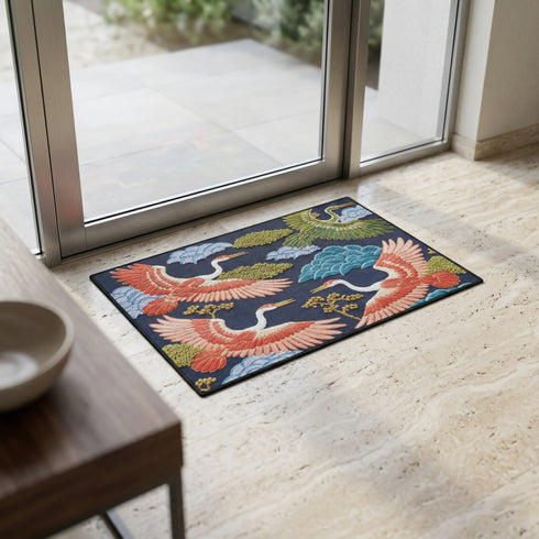 Grimoire and Goblet chinoiserie flying crane faux embroidery doormat featuring three cranes in coral blush and jade green soaring across deep navy background with teal scalloped clouds golden bonsai branches and olive foliage. Printed polyester entryway mat with non-slip rubber backing and black trim. Available 24x18 and 36x24 inches. Asian inspired Japanese crane design housewarming gift home decor