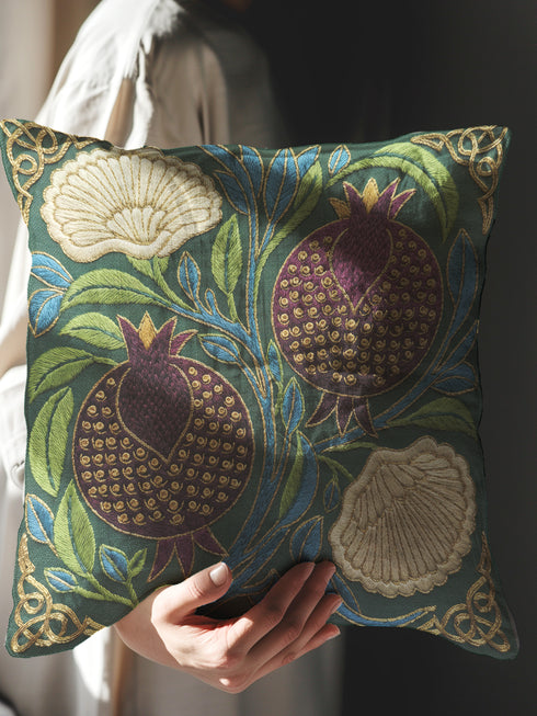 A Grimoire and Goblet decorative pillow cover featuring a Pomegranate and Flower design on a dark midnight teal background. The artwork uses a faux embroidery effect to create the illusion of raised gold and red threadwork on a smooth fabric. The pattern includes red pomegranates, cream carnations, and green leaves in a William Morris style botanical print. Fits Dark Academia, Whimsigoth, and Victorian Gothic decor. Double-sided print with hidden zipper. Cover only.