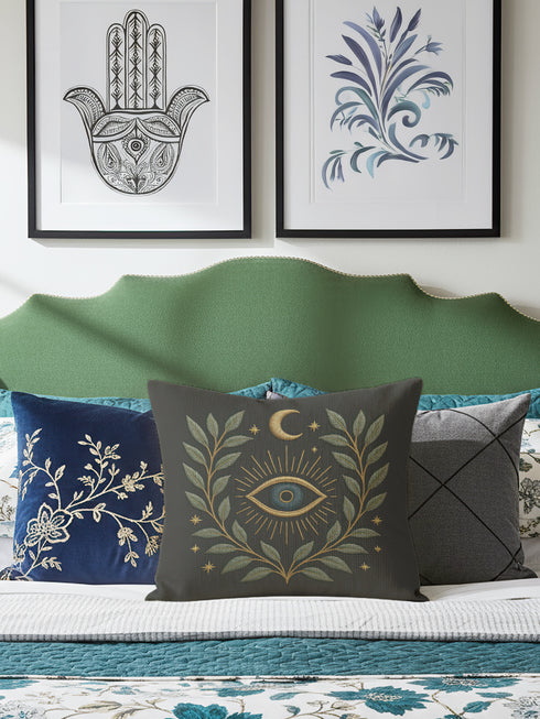 A luxury linen-feel dark gray pillow by Grimoire and Goblet, complete with insert. Features a central, embroidered-look All-Seeing Eye in blue and gold, surrounded by a radiant golden laurel wreath, crescent moon, and stars. Mystical gothic pillow with a seamless zipper.