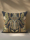 A square decorative throw pillow cover in a deep charcoal gray, almost black, fabric with a subtle linen texture. The pillow features a large, centrally-placed scarab beetle design rendered in a highly detailed, faux-embroidery style. The beetle is symmetrical, with intricate patterns in antique gold, olive green, muted orange, and cream covering its body and head. It is flanked by stylized botanical leaves in matching shades of green and gold.