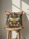 A square black pillow cover made from a pre-shrunk polyester fabric with a soft, linen-like texture. The double-sided, high-fidelity print features a large, central bee with intricate gold and white faux-embroidery on its wings and striped body. Directly above the bee is a golden crescent moon with small stars. The central design is framed by a symmetrical border of botanical elements, including pink thistle-like flowers, white and red daisies, and green leaves.