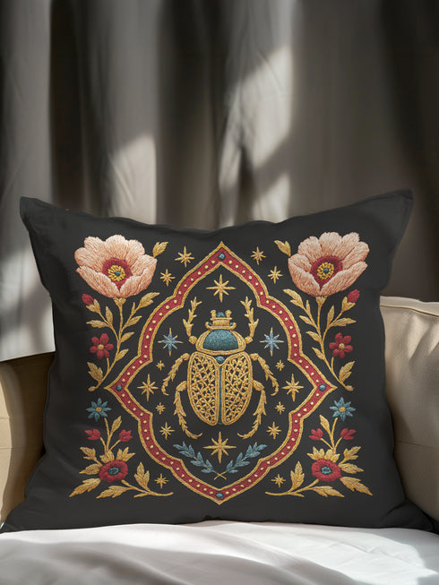 A square, dark charcoal pillow cover with a linen-feel texture, featuring an intricate, embroidered-style design. At the center, a large Egyptian scarab beetle in gold and turquoise is framed by a red and gold quatrefoil border. Symmetrical blush-pink poppies and smaller blue and red flowers with golden foliage flank the central motif, creating a lush botanical scene. Small celestial stars in gold and blue are scattered, adding a mystical, celestial element to this piece of dark academia decor.