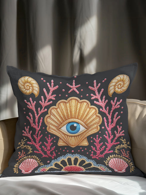 A square decorative pillow cover in a dark charcoal gray with a linen-feel texture. The design features a surrealist, mystical, and nautical goth motif. In the center is a large, golden scallop shell containing a realistic blue and white human eye, serving as an all-seeing eye or protection talisman. The shell is flanked by intricate, embroidered-style pink and red coral branches. The design is bordered by ammonite fossils and smaller seashells, creating dark academia and sea witch aesthetic.