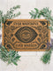 A premium 24x16 inch Grimoire and Goblet Warding Entry Mat featuring a centralized All-Seeing Eye medallion in high-contrast black vinyl on natural tan coconut coir. The design includes radial sunbursts, crescent moons, stars, and botanical roses and thistles. Serif text reads EVER WATCHFUL and EVER WARDED. The rug features a heavy-duty black vinyl backing for weather-resistant stability. Perfect for a luxury Victorian Gothic or Dark Academia entryway sanctuary.