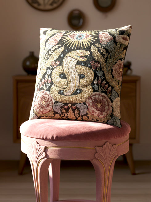 Grimoire and Goblet Celestial Serpent woven tapestry pillow close up. A luxurious black jacquard cushion features a golden coiled snake and All-Seeing Eye surrounded by sage green foliage and stars. The texture is thick and woven, not printed. The serpent scales shimmer in gold thread against a dark charcoal background. Double sided Gothic home decor pillow measuring 17x18 inches. Perfect for Dark Academia, Whimsigoth living rooms, and Year of the Snake 2025 decor.