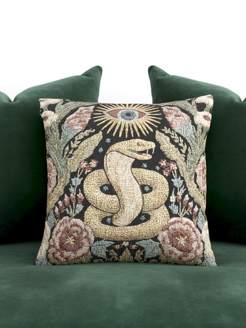 Grimoire and Goblet Celestial Serpent woven tapestry pillow close up. A luxurious black jacquard cushion features a golden coiled snake and All-Seeing Eye surrounded by sage green foliage and stars. The texture is thick and woven, not printed. The serpent scales shimmer in gold thread against a dark charcoal background. Double sided Gothic home decor pillow measuring 17x18 inches. Perfect for Dark Academia, Whimsigoth living rooms, and Year of the Snake 2025 decor.