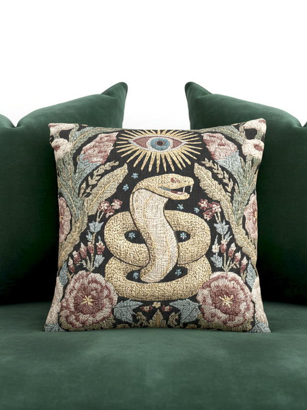 Grimoire and Goblet Celestial Serpent woven tapestry pillow close up. A luxurious black jacquard cushion features a golden coiled snake and All-Seeing Eye surrounded by sage green foliage and stars. The texture is thick and woven, not printed. The serpent scales shimmer in gold thread against a dark charcoal background. Double sided Gothic home decor pillow measuring 17x18 inches. Perfect for Dark Academia, Whimsigoth living rooms, and Year of the Snake 2025 decor.
