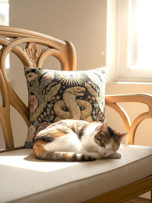 Grimoire and Goblet Celestial Serpent woven tapestry pillow close up. A luxurious black jacquard cushion features a golden coiled snake and All-Seeing Eye surrounded by sage green foliage and stars. The texture is thick and woven, not printed. The serpent scales shimmer in gold thread against a dark charcoal background. Double sided Gothic home decor pillow measuring 17x18 inches. Perfect for Dark Academia, Whimsigoth living rooms, and Year of the Snake 2025 decor.