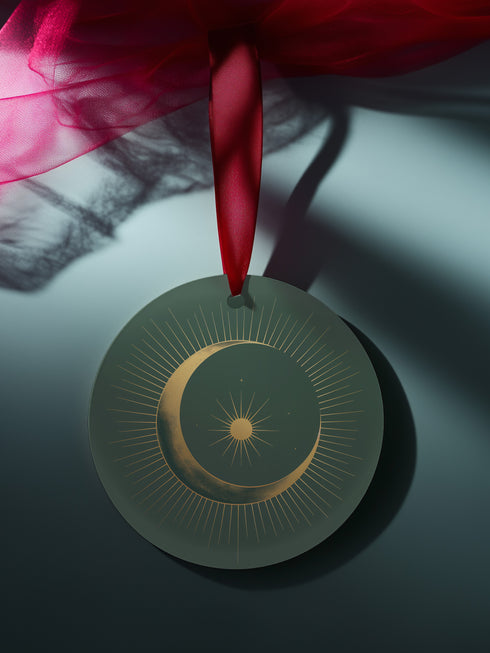 Round metal ornament featuring golden crescent moon and star design with Art Deco sunburst pattern on black background. 3.5-inch diameter piece with celestial motifs and crimson ribbon. Double-sided astronomical artwork.