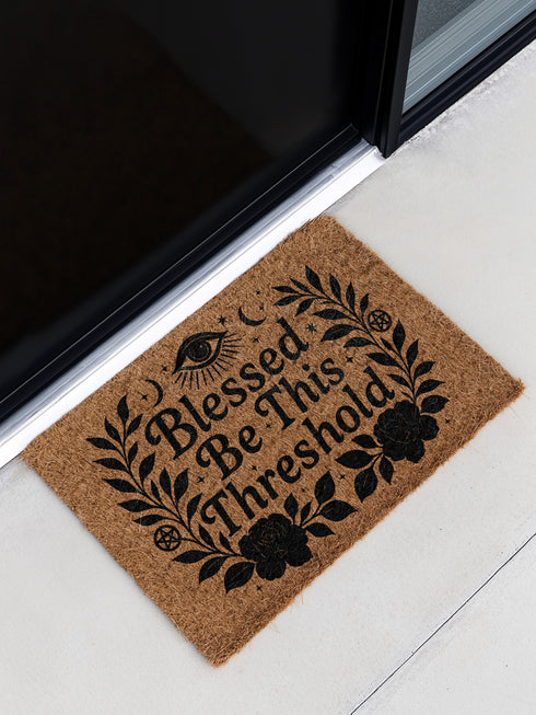 Eco-friendly coir doormat with mystical black print reading “Blessed Be This Threshold,” featuring occult symbols like crescent moons, pentacles, all-seeing eye, and roses, styled on various front steps and entryways including outdoor stoops and interiors with pets, ideal for witchy home décor and spiritual gifting.