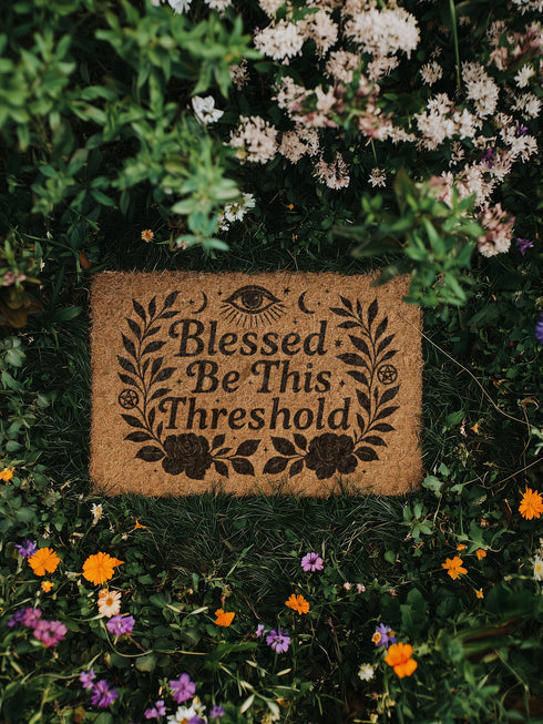 Eco-friendly coir doormat with mystical black print reading “Blessed Be This Threshold,” featuring occult symbols like crescent moons, pentacles, all-seeing eye, and roses, styled on various front steps and entryways including outdoor stoops and interiors with pets, ideal for witchy home décor and spiritual gifting.
