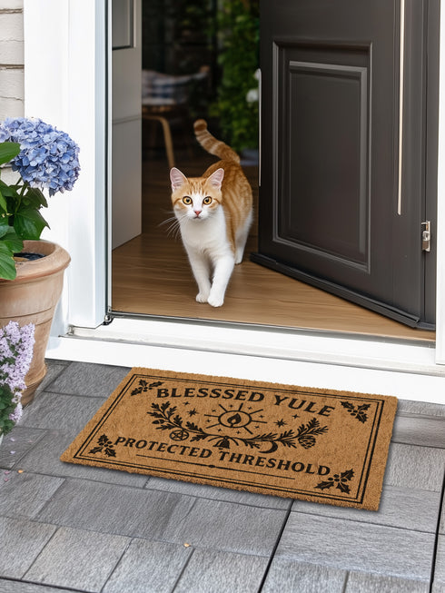 A rectangular tufted coir doormat with a non-slip black vinyl backing, features an intricate gothic botanical design in black. At the top, it reads "BLESSED YULE" with holly motifs in the corners. In the center, a laurel wreath, intertwined with a pentacle and a bell, encircles a radiant candle. Below the wreath rests a pinecone. At the bottom, the text "PROTECTED THRESHOLD" is flanked by holly. This pagan and witchy Grimoire and Goblet design is perfect for a gothic or dark academia entryway.