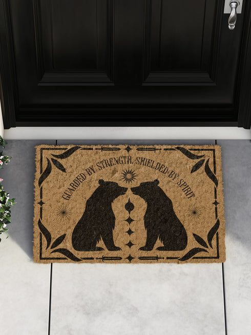 Natural coir doormat featuring two black bear silhouettes facing each other, surrounded by botanical and celestial accents. The mat is made from eco-friendly coir fiber with a slip-resistant vinyl backing, ideal for outdoor use in covered entryways.