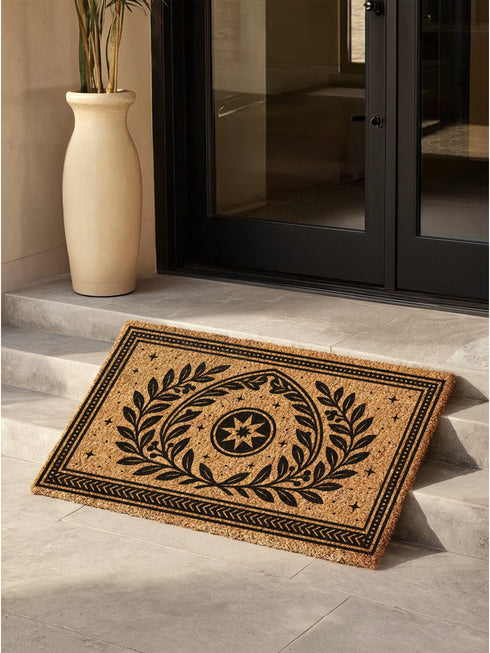 A rectangular natural coir doormat with a durable, non-slip black vinyl backing. The surface features an intricate black gothic-style design centered around an eight-pointed celestial star. This mystical symbol is encircled by a pointed arch formed from two botanical laurel branches, symbolizing wisdom and protection. The central motif is framed by a double border with geometric details and smaller stars. A perfect piece of spiritual home decor for a pagan or mystical entryway.