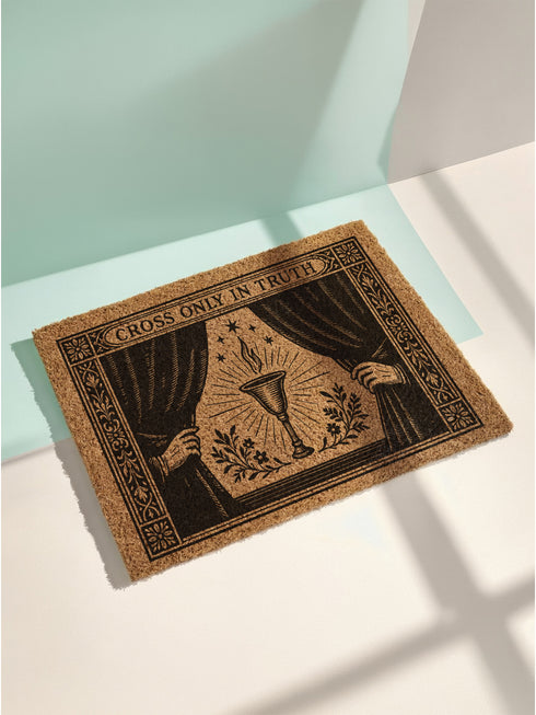 A rectangular doormat made from natural, textured brown coir fiber, featuring a striking black gothic design for spiritual threshold protection. The centerpiece of this witchy welcome mat is a sacred flaming chalice, set between two parted curtains for a dramatic entryway statement. Above the occult imagery, the phrase 'Cross Only In Truth' is printed in a mystical font reminiscent of ancient spellbooks, making this metaphysical and dark academia decor a powerful symbol for a protected home. This is a doorm