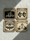 Set of four 4-inch square anatomical love coasters by Grimoire and Goblet. Each coaster features a black ink illustration on an antique tan parchment background in a Victorian scientific style. Designs include linked anatomical hearts for "De Humani Cordis," a triquetra and alchemy flasks for "The Alchemical Bond," a Death's Head moth for "The Moth & The Flame," and a study of neck nerves for "Nervus Amoris." Ideal for a Victorian grimoire aesthetic and gothic romance home bar decor.