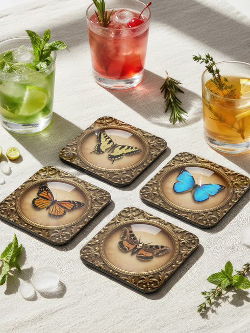 Set of four Gothic Entomology Coasters featuring square, ornate gold frames surrounding taxidermy-inspired butterfly and moth specimen prints in high-gloss finish. Ideal barware from Grimoire and Goblet for Dark Academia and witchy home decor.