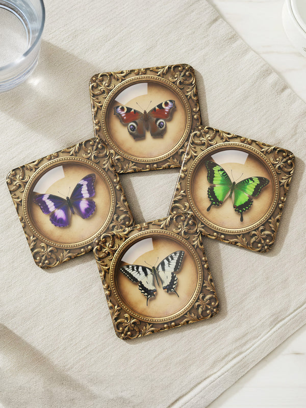 Grimoire and Goblet offers this luxury four-piece square Coaster Set featuring glossy, dome-covered, Taxidermy-inspired Entomology butterfly specimens, framed in ornate Victorian Gothic style. The resilient hardboard foundation and non-slip cork backing provide premium, waterproof protection for fine cocktails and esoteric teas. The collection includes purple, green, white, and peacock butterfly art, ideal for Dark Academia, Oddity, and Curio Cabinet decor.