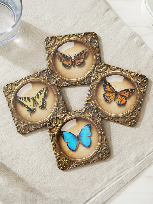 Set of four Gothic Entomology Coasters featuring square, ornate gold frames surrounding taxidermy-inspired butterfly and moth specimen prints in high-gloss finish. Ideal barware from Grimoire and Goblet for Dark Academia and witchy home decor.