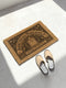 Threshold Doormat featuring a black Gothic arched doorway design on natural tan coir. The design includes a central eight-pointed star sunburst octagram symbol inside the arch, flanked by symmetrical laurel branches and corner ivy vine filigree. This 24x16 protective threshold mat is made of eco-friendly coconut fiber with a stable black vinyl backing. Ideal as a witchy housewarming gift or dark academia entry rug, this warding mat functions as a symbolic threshold guardian for a mystical home.