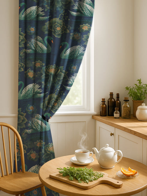 Grimoire and Goblet blackout curtain panel featuring a repeating Art Nouveau pattern of regal white swans and lush emerald green peonies on a deep midnight navy blue background. The design includes floating lily pads and stylized floral foliage with hints of ochre gold. The fabric is 100% heavyweight polyester with a satin finish and a rod pocket header. The print mimics the look of vintage embroidery but is a smooth, high-quality flat print.
