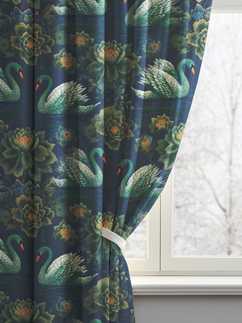 Grimoire and Goblet blackout curtain panel featuring a repeating Art Nouveau pattern of regal white swans and lush emerald green peonies on a deep midnight navy blue background. The design includes floating lily pads and stylized floral foliage with hints of ochre gold. The fabric is 100% heavyweight polyester with a satin finish and a rod pocket header. The print mimics the look of vintage embroidery but is a smooth, high-quality flat print.