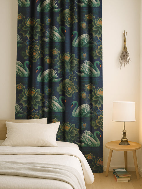 Grimoire and Goblet blackout curtain panel featuring a repeating Art Nouveau pattern of regal white swans and lush emerald green peonies on a deep midnight navy blue background. The design includes floating lily pads and stylized floral foliage with hints of ochre gold. The fabric is 100% heavyweight polyester with a satin finish and a rod pocket header. The print mimics the look of vintage embroidery but is a smooth, high-quality flat print.