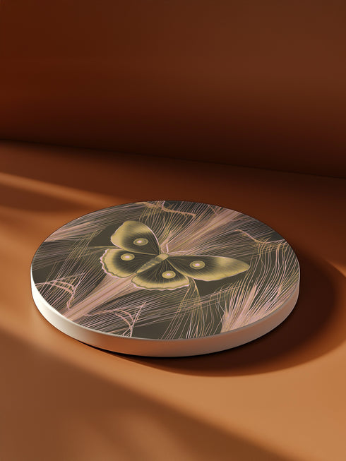 Round ceramic coaster featuring golden Luna moth illustration on dark green background with rose gold linear patterns. Cork-backed, 4-inch diameter. Perfect for vintage nature and gothic decor enthusiasts.