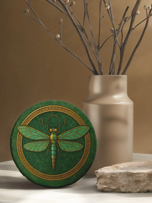 Round ceramic coaster featuring a raised gold-tone dragonfly relief and ornate border on a deep green glazed surface; 4-inch diameter; backed with natural cork for non-slip stability; heat- and cold-resistant; easy-wipe ceramic top; ideal for mystical, botanical, or occult-inspired tabletops.