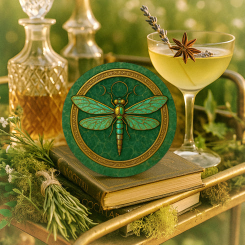 Round ceramic coaster featuring a raised gold-tone dragonfly relief and ornate border on a deep green glazed surface; 4-inch diameter; backed with natural cork for non-slip stability; heat- and cold-resistant; easy-wipe ceramic top; ideal for mystical, botanical, or occult-inspired tabletops.
