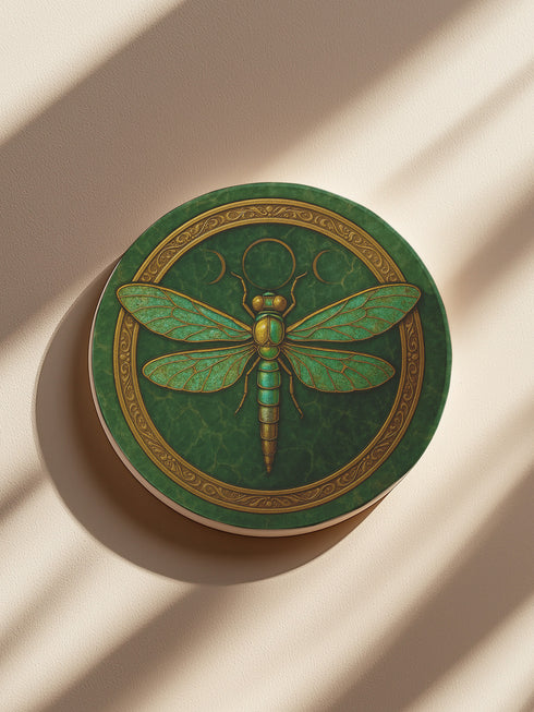 Round ceramic coaster featuring a raised gold-tone dragonfly relief and ornate border on a deep green glazed surface; 4-inch diameter; backed with natural cork for non-slip stability; heat- and cold-resistant; easy-wipe ceramic top; ideal for mystical, botanical, or occult-inspired tabletops.