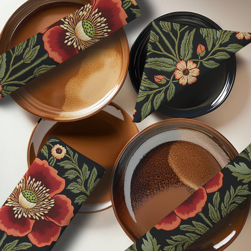 A four-piece cloth napkin set featuring oversized embroidered-style red poppy flowers with green foliage on a deep black background; square-shaped, made of soft polyester with one-sided print and white reverse.