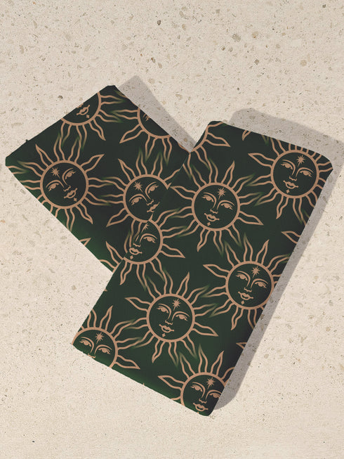 Set of four forest green cloth napkins featuring a gold sun motif, made from polyester, measuring 18'' × 18''.