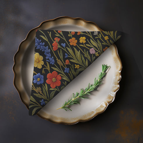 Four-piece cloth napkin set featuring a richly embroidered-style wildflower motif on a deep black background. Includes yellow, red, blue, and orange florals with intricate green stems and leaves. Each napkin is printed on one side and measures 18 x 18 inches, made from smooth polyester fabric with white backing.