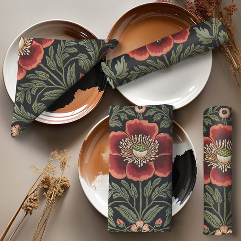 A four-piece cloth napkin set featuring oversized embroidered-style red poppy flowers with green foliage on a deep black background; square-shaped, made of soft polyester with one-sided print and white reverse.