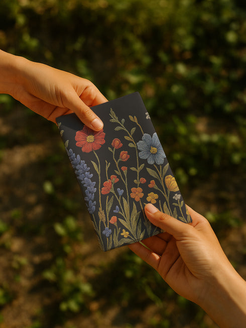 Four-piece cloth napkin set featuring a richly embroidered-style wildflower motif on a deep black background. Includes yellow, red, blue, and orange florals with intricate green stems and leaves. Each napkin is printed on one side and measures 18 x 18 inches, made from smooth polyester fabric with white backing.