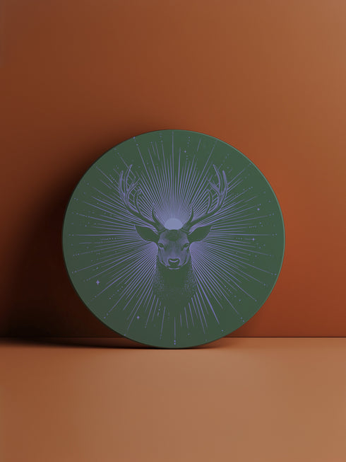 Ceramic coasters in round and square shapes featuring a detailed deer head with antlers on a forest green background, surrounded by radiating periwinkle blue sunburst lines and small stars, with protective cork backing.